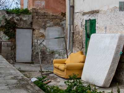 Ci avviciniamo dunque ai caseggiati, dove ad accoglierci ci sono un divano giallo e un materasso appoggiati a una parete...